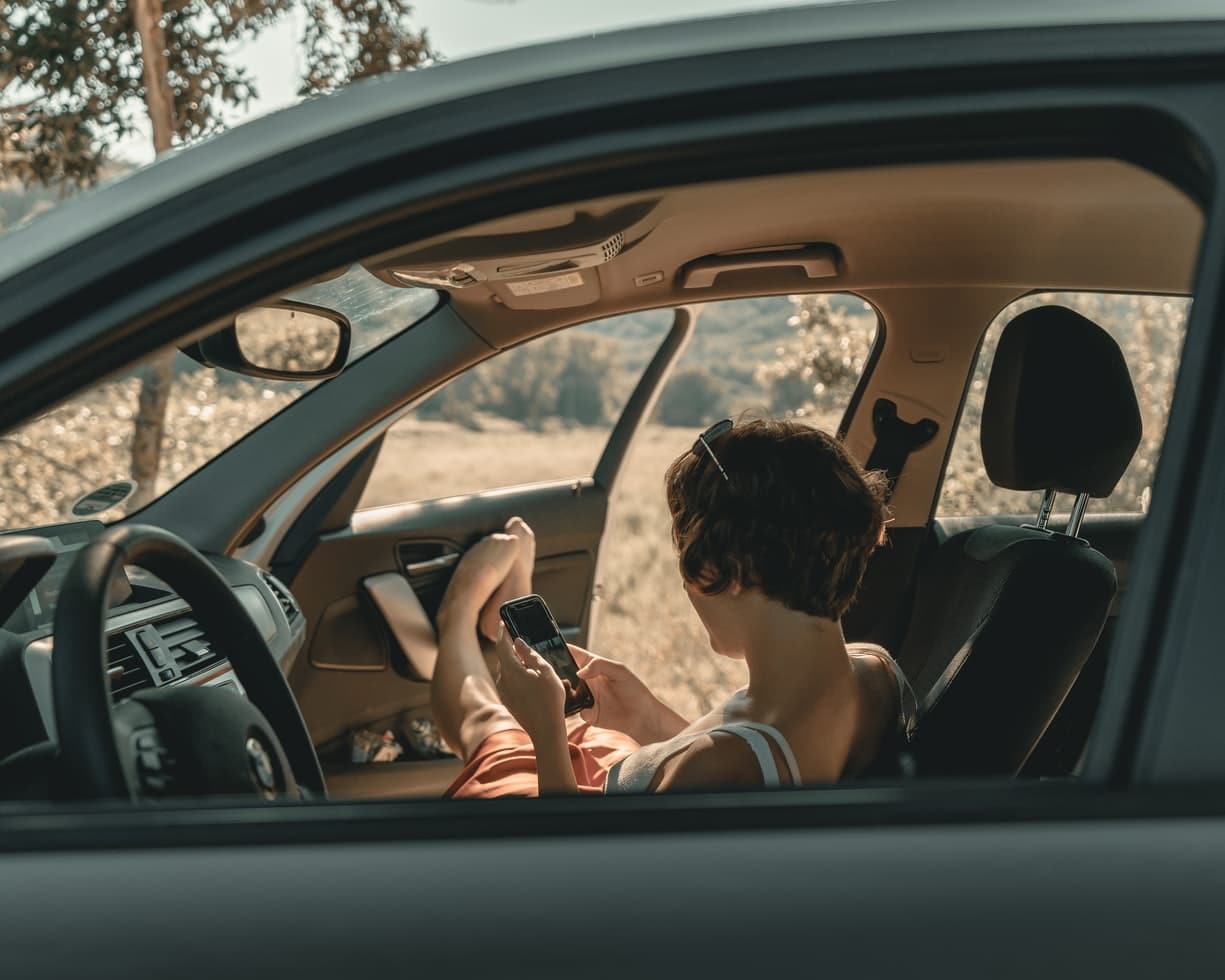 mujer sentada en el interior de un coche con las puertas abiertas